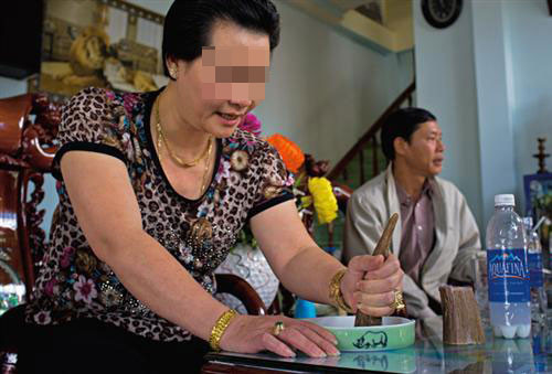 Một người phụ nữ Việt Nam dùng miếng sừng tê giác mài vào bát đựng ít nước và tin rằng bột sừng chữa được sỏi thận.