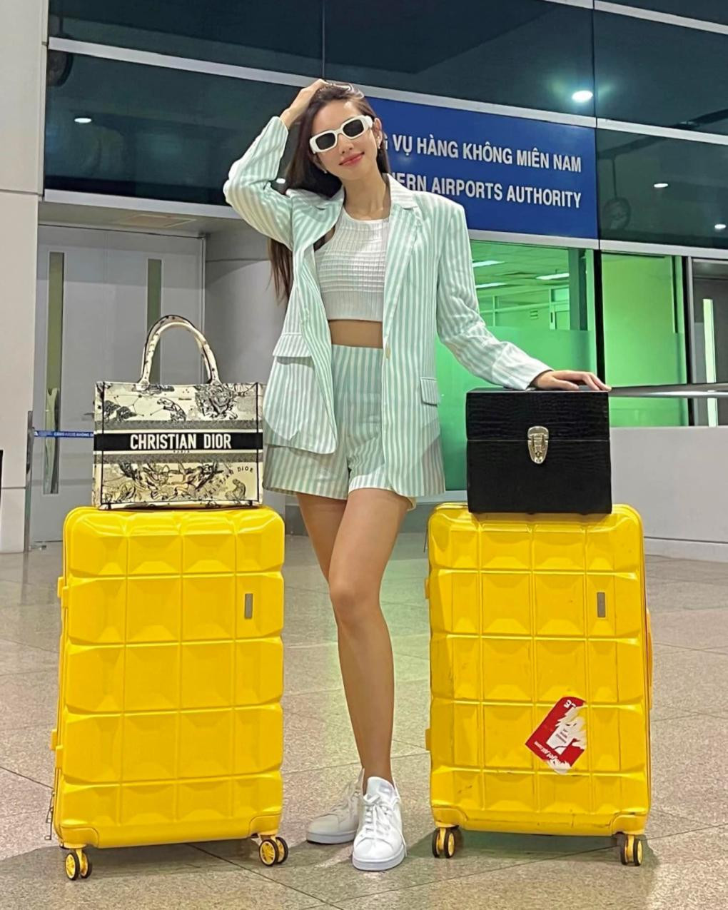 Suit kẻ sọc, mắt kính trắng và sneaker giúp thời trang sân bay của Thùy Tiên thoải mái nhưng không kém phần trendy.