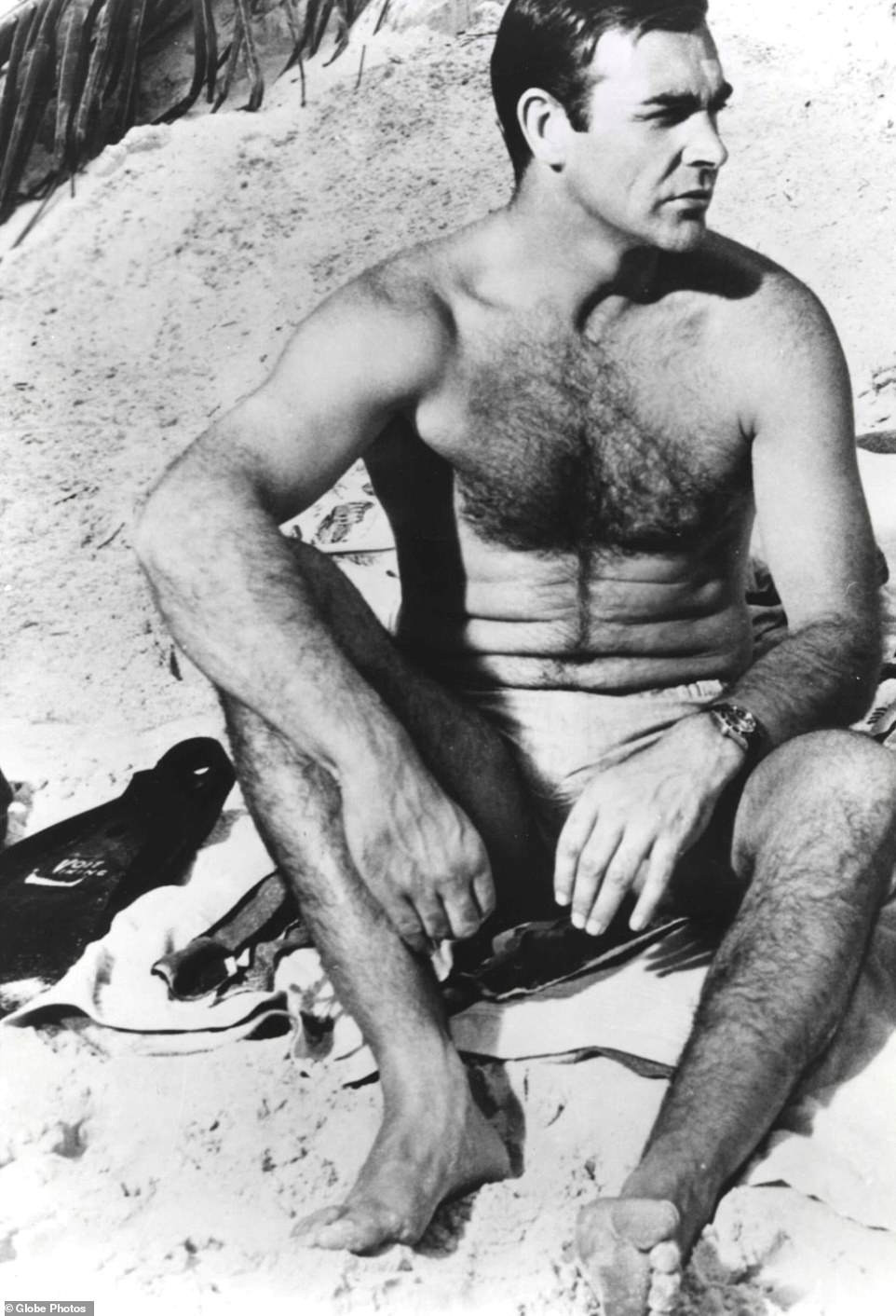 Sean Connery trông rắn rỏi khi ngồi trên bãi cát ở Bahamas trên phim trường Thunderball năm 1965 trong vai điệp viên 007 James Bond.