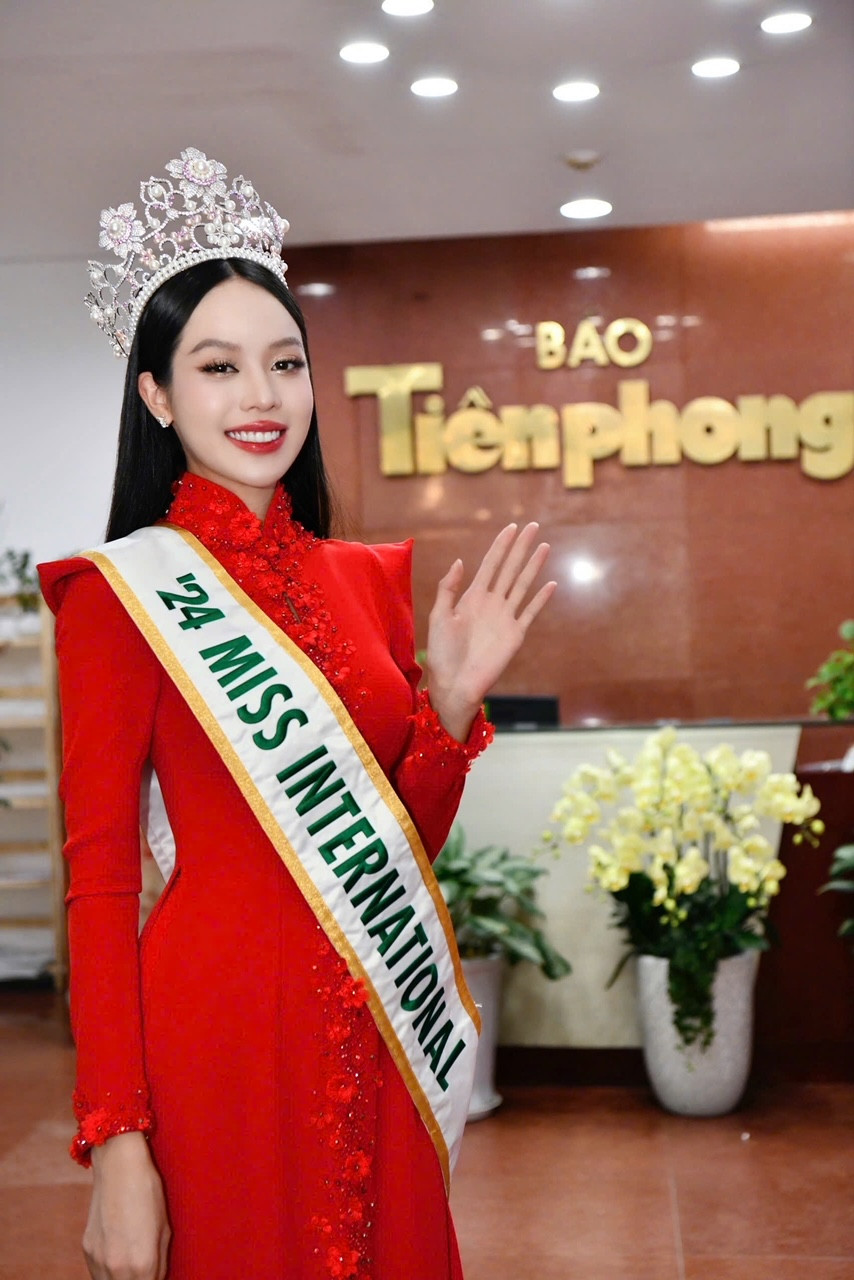 Người đẹp sinh năm 2002 xuất hiện rực rỡ trong tà áo dài truyền thống đỏ tươi và vương miện Hoa hậu Quốc tế 2024 khi trở về mái nhà Tiền Phong sau hành trình nỗ lực và thăng hoa cảm xúc. (Ảnh: Trọng Tài)
