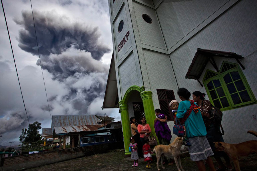 Dân làng đứng bên ngoài một nhà thờ sau khi núi lửa Sinabung phun trào ngày 24/11/02013 tại làng Simpang Empat thuộc huyện Karo, phía bắc đảo Sumatra, Indonesia
