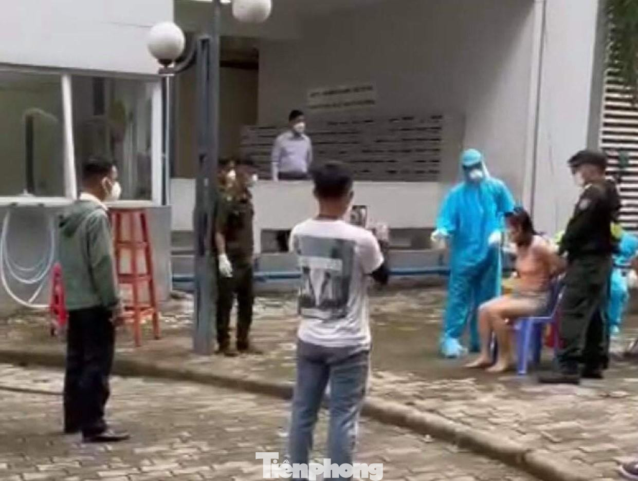 Người phụ nữ bị cưỡng chế do không tự xuống sân chung cư xét nghiệm. - Ảnh chụp từ clip