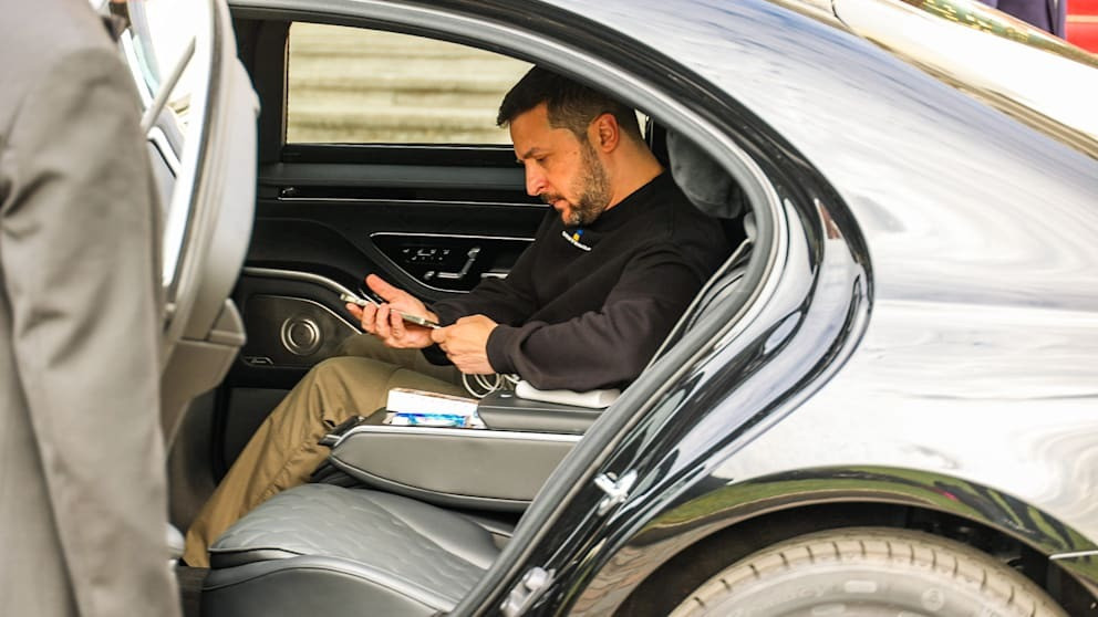 Ông Zelensky dùng điện thoại cắm sạc dự phòng trên xe hơi. Ảnh: Bild