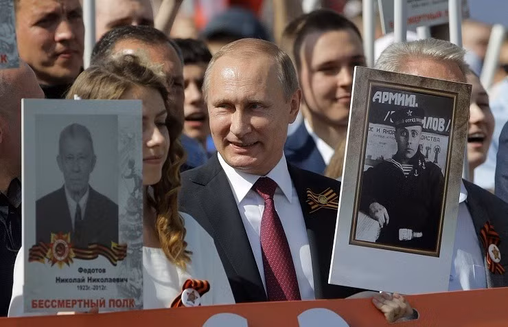 Tổng thống Vladimir Putin cầm bức chân dung của cha - ông Vladimir Spiridonovich Putin, người từng chiến đấu trong Thế chiến II - khi tham gia cuộc tuần hành Trung đoàn bất tử hồi năm 2016. Ảnh: Tass