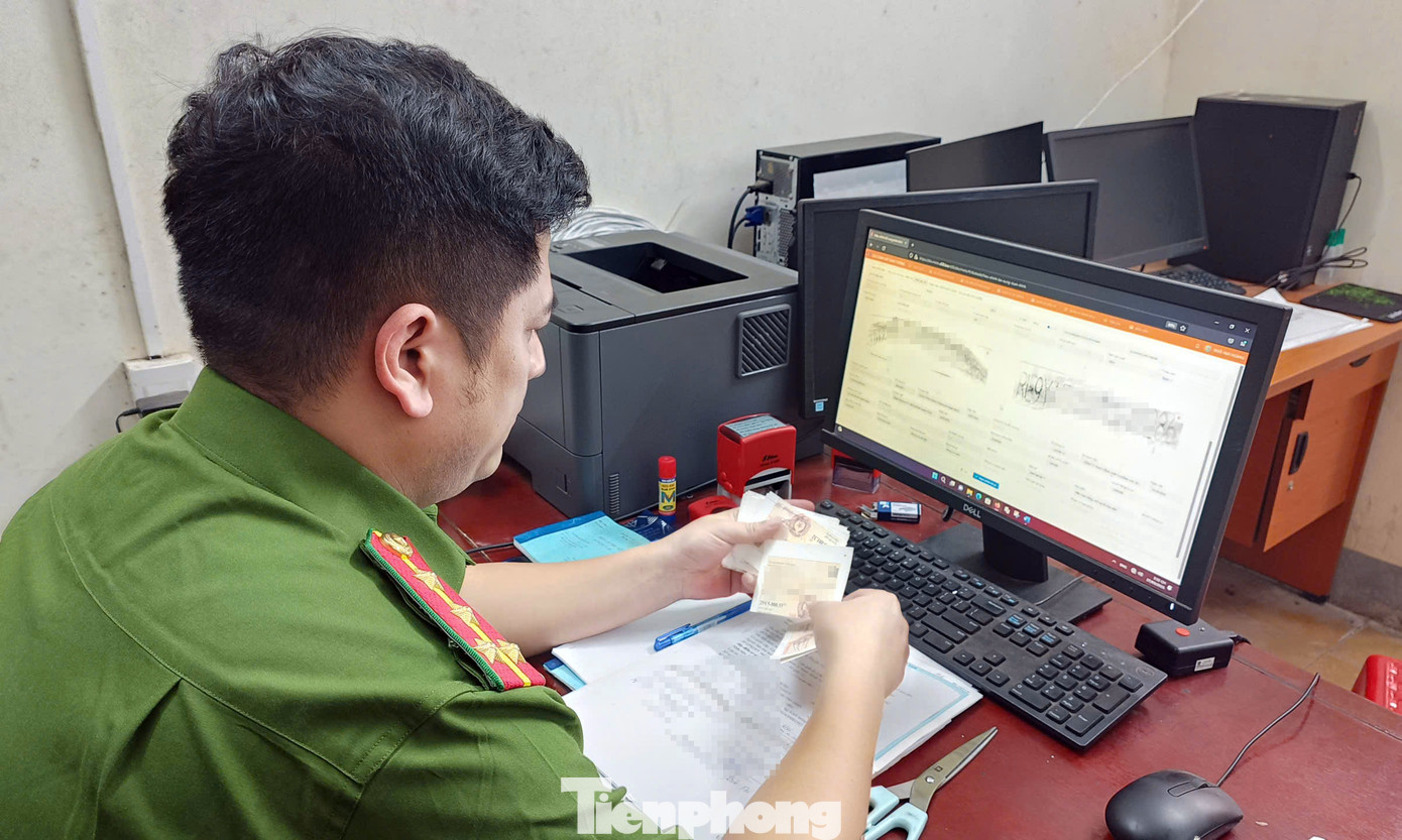 Đại úy Ngô Huy Hoàng kiểm tra hồ sơ, biển số xe người dân đến làm thủ tục.