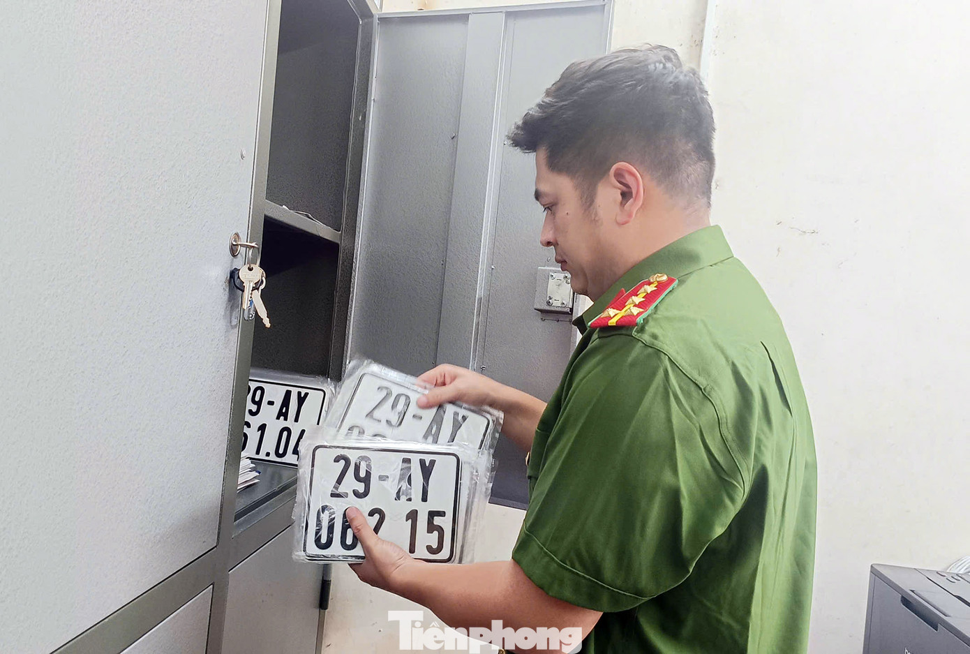 Đại úy Ngô Huy Hoàng kiểm tra hồ sơ, biển số xe người dân đến làm thủ tục.