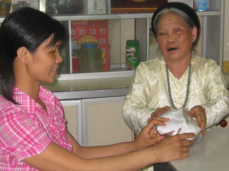 Lương y Nguyễn Thị Hậu (bên phải) trao thuốc cho bệnh nhân. Ảnh: Việt Hà 