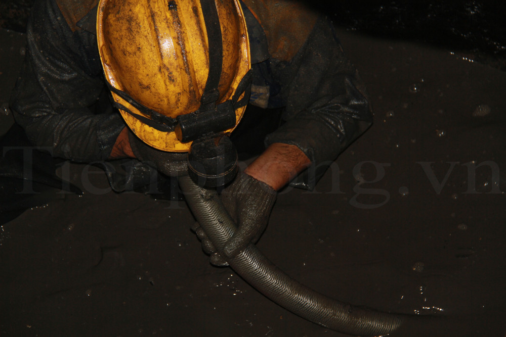 Chiếc ống nối với cống bên cạnh bị tắc, một công nhân ghé miệng vào thổi, dù chiếc ống dính đầy bùn bẩn. Ảnh: Trường Phong