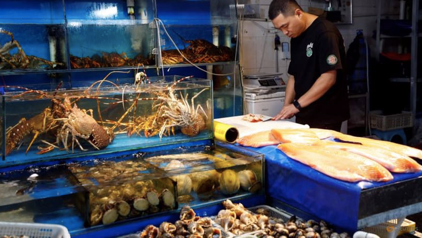 Một người bán hàng sơ chế hải sản tại quầy ở chợ hải sản Bắc Kinh, Trung Quốc, ngày 24/8. (Ảnh: Reuters)