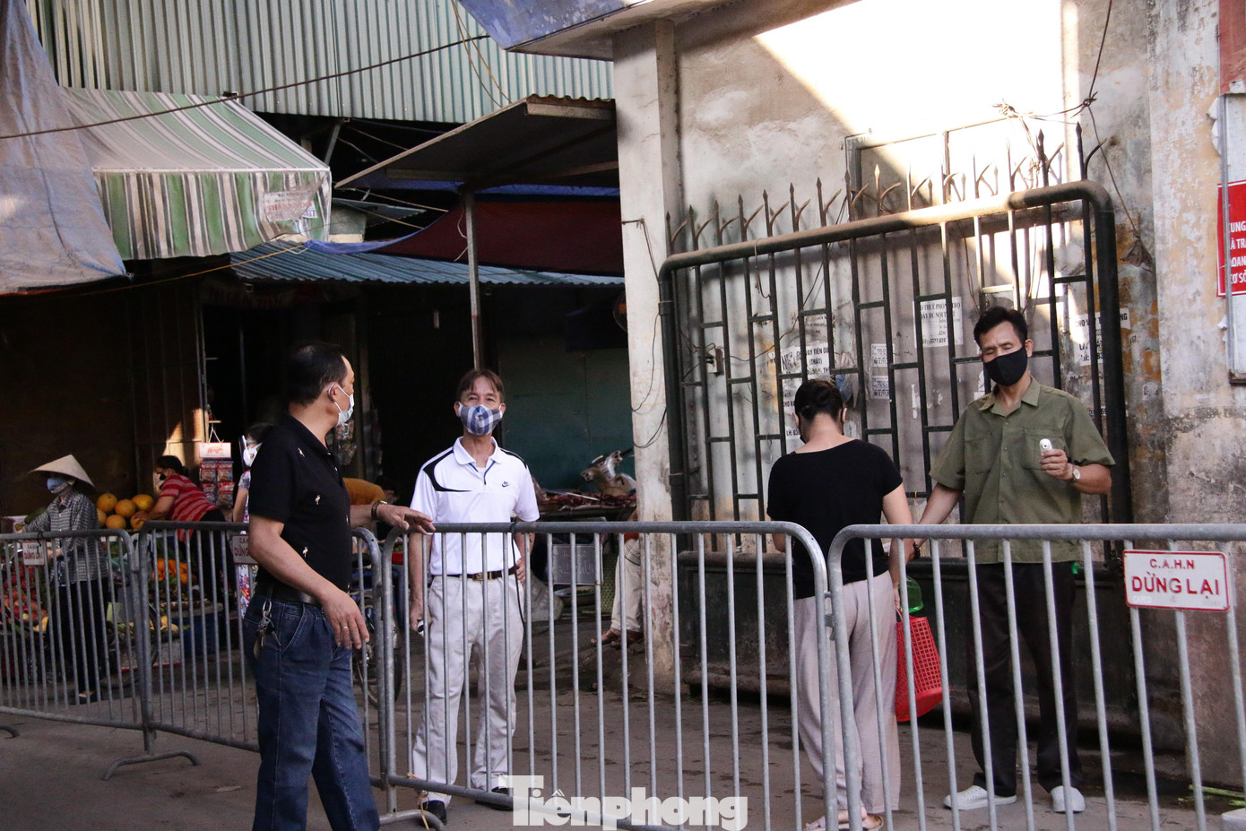 Người dân trước khi vào chợ sẽ được kiểm tra phiếu ra vào, đo thân nhiệt và sát khuẩn tay tại cửa kiểm soát.