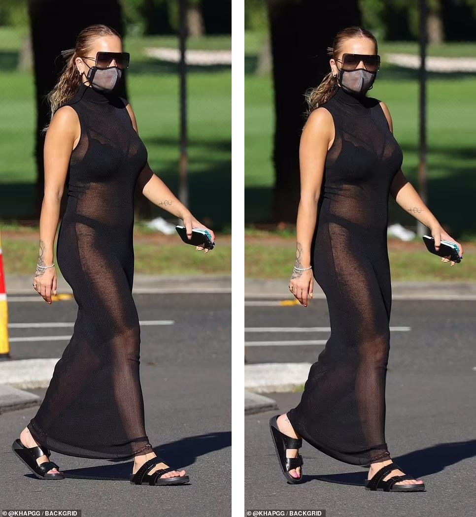 Nữ ca sĩ &quot;50 sắc thái&quot; mặc váy maxi không tay, cổ lọ màu đen dài đến mắt cá chân, kết hợp với dép bệt và mắt kính &quot;ton-sur-ton&quot;. Tóc buộc đuôi ngựa gọn gàng.