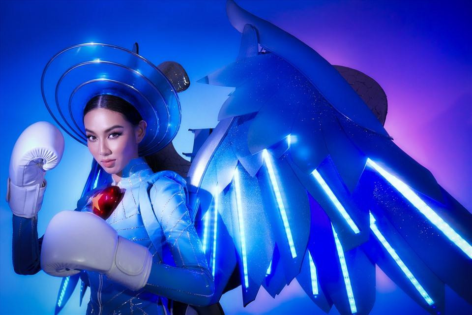 Sắc xanh chủ đạo của bộ trang phục được lấy cảm hứng từ màu áo bảo hộ của lực lượng chống dịch. Phía sau là phần cách điệu đôi rắn mạ vàng và điêu khắc thủ công quấn quanh ống tiêm vaccine cùng với đôi cánh sơn hiệu ứng ombre ánh kim, tạo nên hình ảnh biểu trưng của ngành Y. Những chi tiết này sẽ giúp phần trình diễn của Thùy Tiên trên sân khấu trở nên bắt mắt và thu hút hơn.