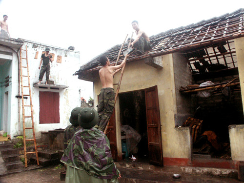 Các chiến sĩ giúp dân lớp lại mái nhà