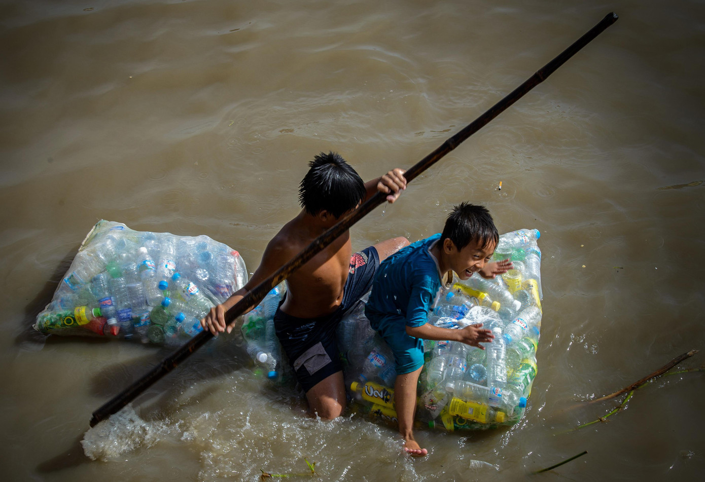 Trẻ em miền Tây vừa gom chai nhựa trên sông nước vừa tạo thành một cái bè để di chuyển. Ảnh: Kha Trí Thành Đạt.