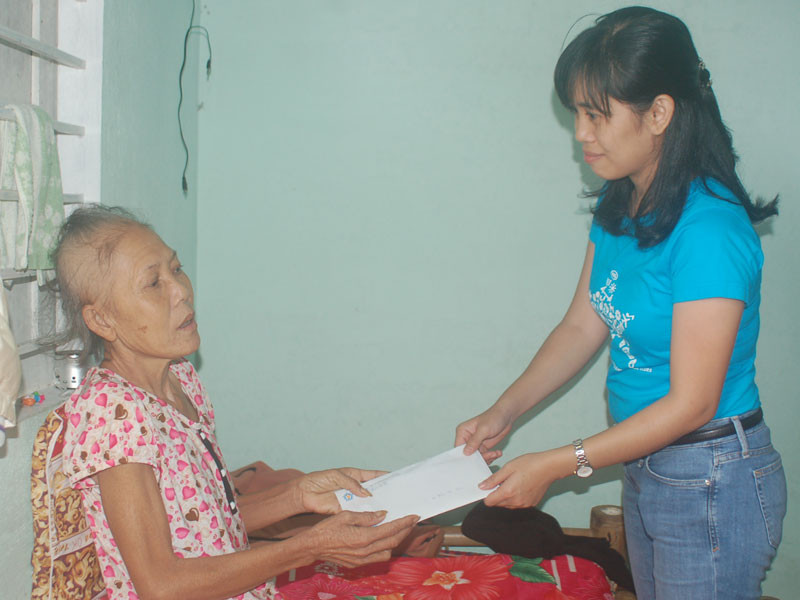 Bà Đoàn Đỗ Ngọc Thi thăm và trao quà cho bà Trần Thị Mười bên giường bệnh tại căn nhà bà Mười đang ở nhờ, xã Điện Dương, Huyện Điện Bàn, tỉnh Quảng Nam