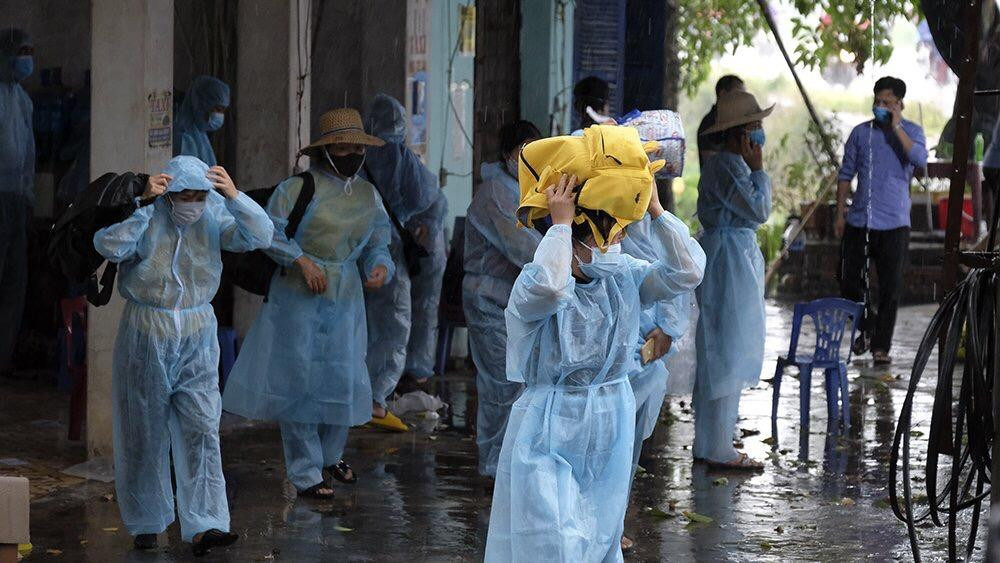 Những người còn lại sau khi được lấy mẫu xét nghiệm, mặc đồ bảo hộ lên xe di chuyển đến điểm cách ly tập trung. Ảnh: Hoàng Mạnh Thắng