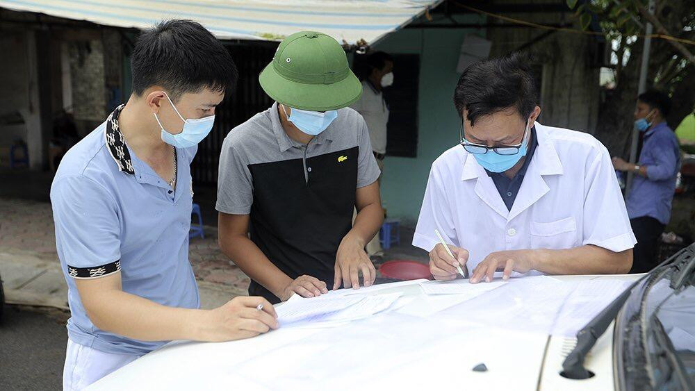 Ngay đầu con đường dẫn vào thôn Kênh Đào, lực lượng chức năng phối hợp với lực lượng y tế trưng dụng một cửa hàng sửa chữa xe máy làm nơi rà soát các trường hợp liên quan, xét nghiệm trước khi đưa các trường hợp nguy cơ cao đi cách ly tập trung. Ảnh: Hoàng Mạnh Thắng