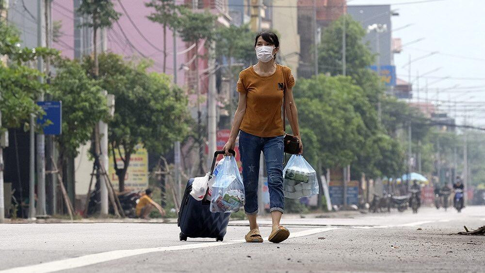 Một phụ nữ mang theo nhiều đồ đạc, chuẩn bị cho nhiều ngày cách ly tập trung sắp tới. Nhiều trường hợp tương tự như chị này cũng phải đi cách ly tập trung để phòng chống dịch bệnh. Trò chuyện với nhau, nhiều người bảo chưa kịp lo công việc ở nhà trước khi đi. Ảnh: Hoàng Mạnh Thắng
