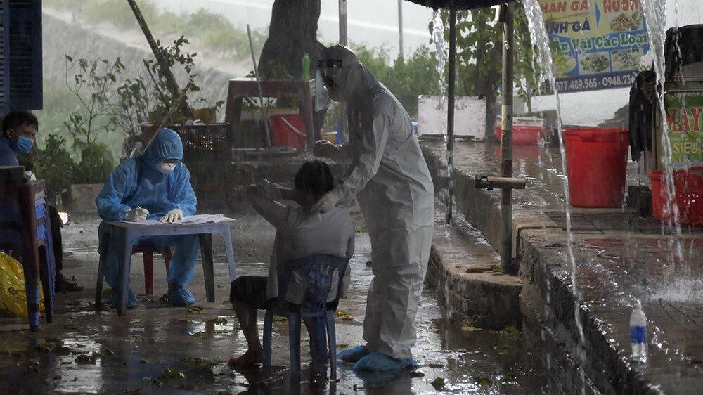 Cơn mưa lớn chiều 7/7 không ngăn được việc lấy mẫu xét nghiệm ở cửa hàng sửa chữa xe máy bên đường. Ảnh: Hoàng Mạnh Thắng