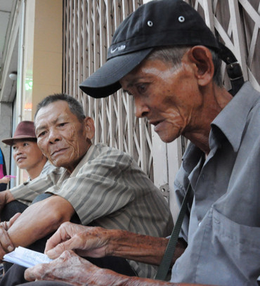 Ông Hai Minh (bìa phải) dù đã lớn tuổi phải đi bán vé số vẫn bị kẻ lừa đảo nhắm đến