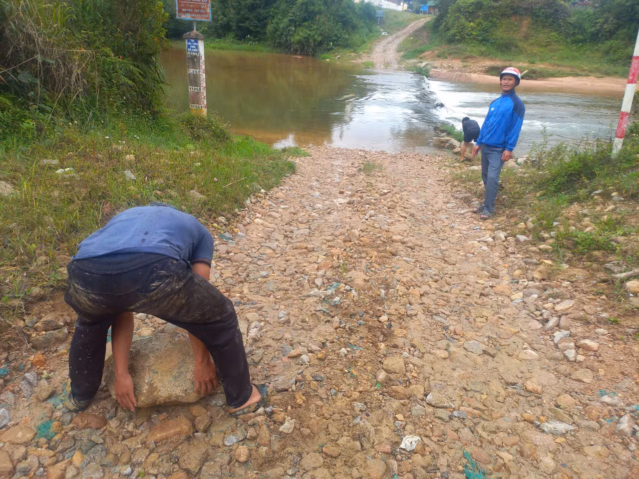 Người dân phải khuân đá để gia cố 2 bên ngầm giúp xe cộ có thể di chuyển khi nước rút