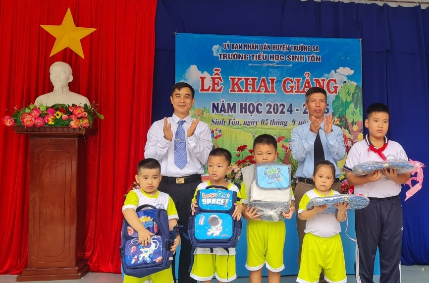 Đại diện UBND xã và trường tiểu học Sinh Tồn tặng quà cho các cháu trong ngày khai giảng.