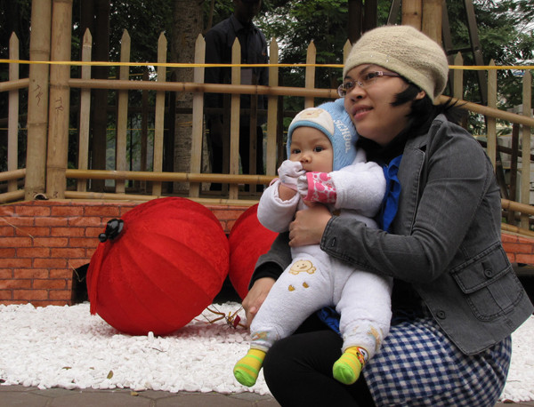 Một bà mẹ bế con thơ đi xem hội