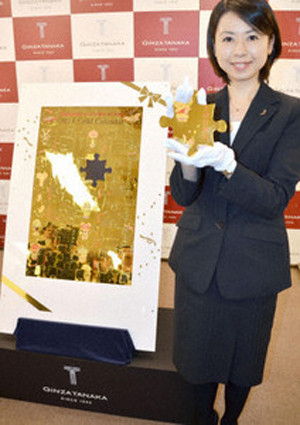 Một nhân viên của Ginza Tanaka giới thiệu cuốn lịch vàng 2014. Ảnh: Kyodo News