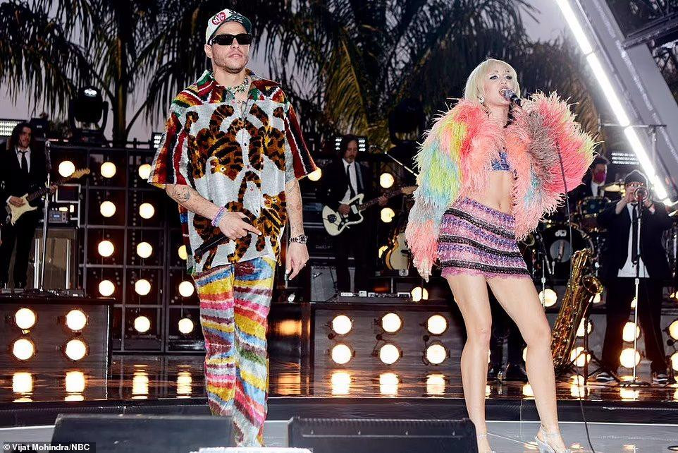 Khi biểu diễn ca khúc &quot;Miami&quot; của Will Smith cùng bạn trai Kim Kardashian, Miley diện áo bra kết hợp chân váy siêu ngắn và áo khoác tua rua nhiều màu sắc.