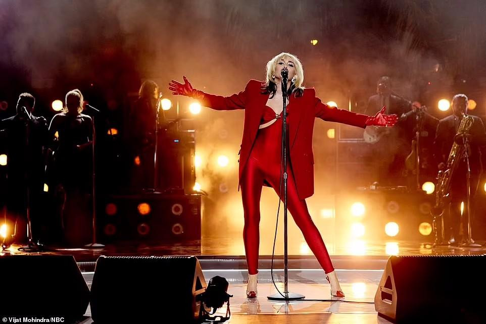 Khi cover ca khúc &quot;Heart Of Glass&quot; của Blondie, Miley mặc jumpsuit đỏ bó sát, kết hợp áo blazer &quot;ton-sur-ton&quot;. Được biết, đây chính là chiếc áo &quot;cứu cánh&quot; Miley lúc gặp sự cố rơi áo.
