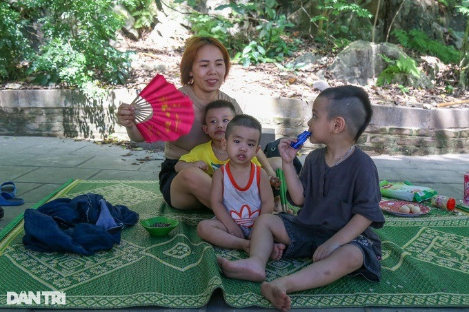 Vợ chồng bà Bình đưa 3 cháu nhỏ lên chùa trốn nắng nóng. Bà chia sẻ ở nhà nóng không chịu được, hai vợ chồng thay phiên nhau quạt cho cháu, mỏi rã cả tay.