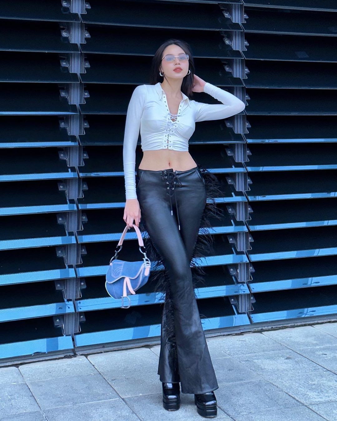 Thời gian gần đây, Hoa hậu Thanh Thủy bắt đầu có những thay đổi lớn trong phong cách thời trang, đặc biệt là street style. Người đẹp hướng tới phong cách Y2K vừa cá tính, vừa dễ thương. Set đồ bao gồm áo sơ-mi khoét vòng 1 táo bạo kết hợp cùng quần da ống loe mang lại vẻ thời thượng, sành điệu cho người đẹp Đà Nẵng.