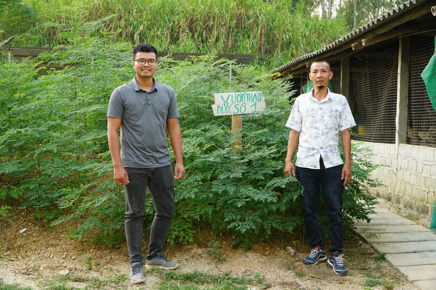 Anh Hà Minh Nguyện (trái) và anh Lại Thành Biên bên vườn thảo dược của trang trại.