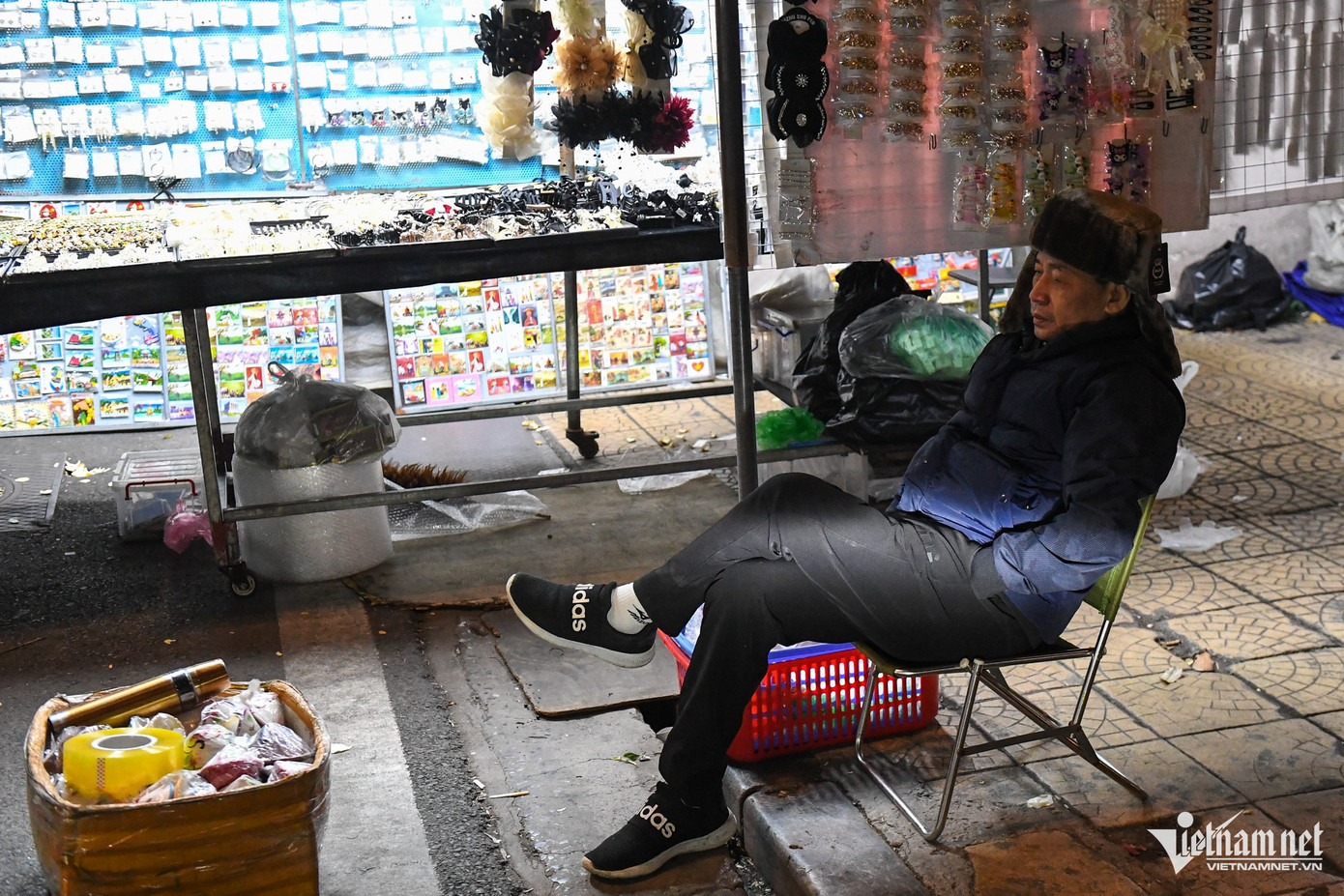 Tại chợ đêm Đồng Xuân, một người bán hàng co ro ngồi chờ khách. 0h30, nhiều tiểu thương của các sạp hàng quanh đó đã rục rịch dọn đồ ra về sớm hơn thường lệ. Tại chợ đêm Đồng Xuân, một người bán hàng co ro ngồi chờ khách. 0h30, nhiều tiểu thương của các sạp hàng quanh đó đã rục rịch dọn đồ ra về sớm hơn thường lệ.