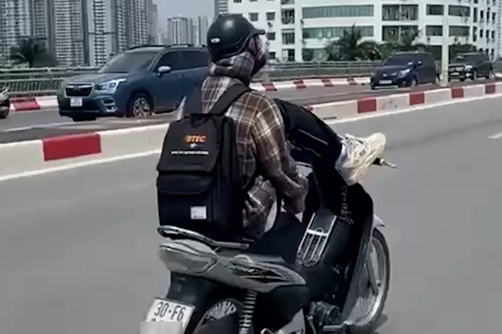 Hình ảnh nam thanh niên dùng chân lái xe máy. Ảnh chụp màn hình
