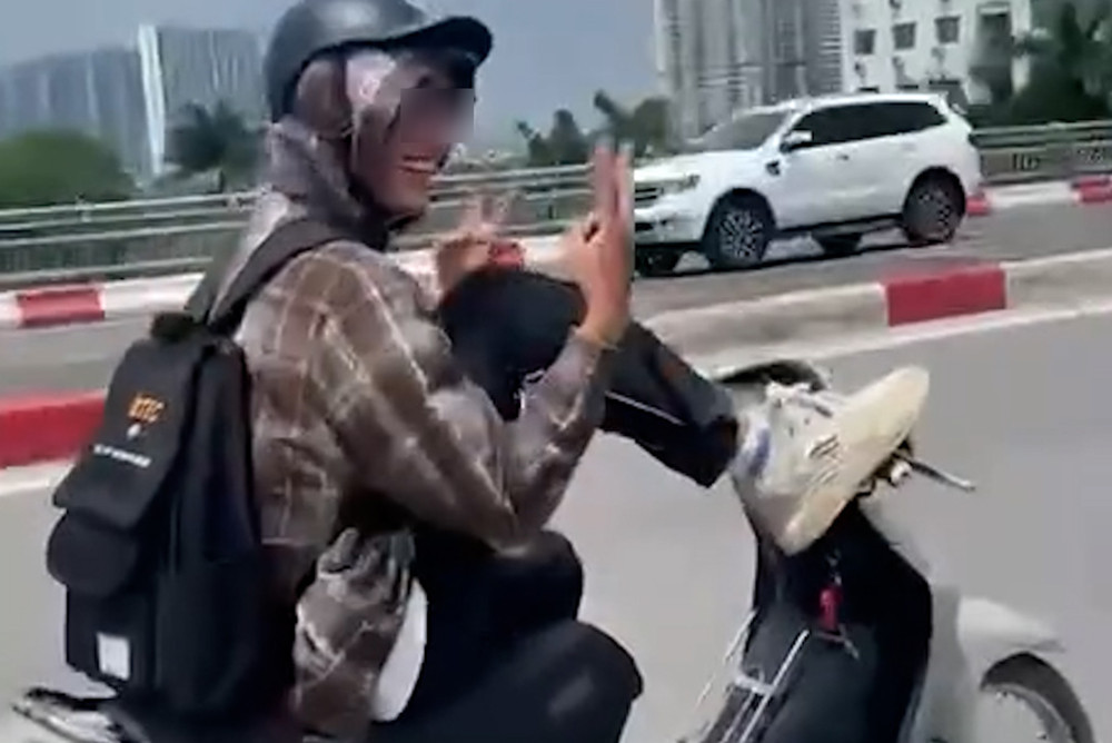 Hình ảnh nam thanh niên dùng chân lái xe máy. Ảnh chụp màn hình