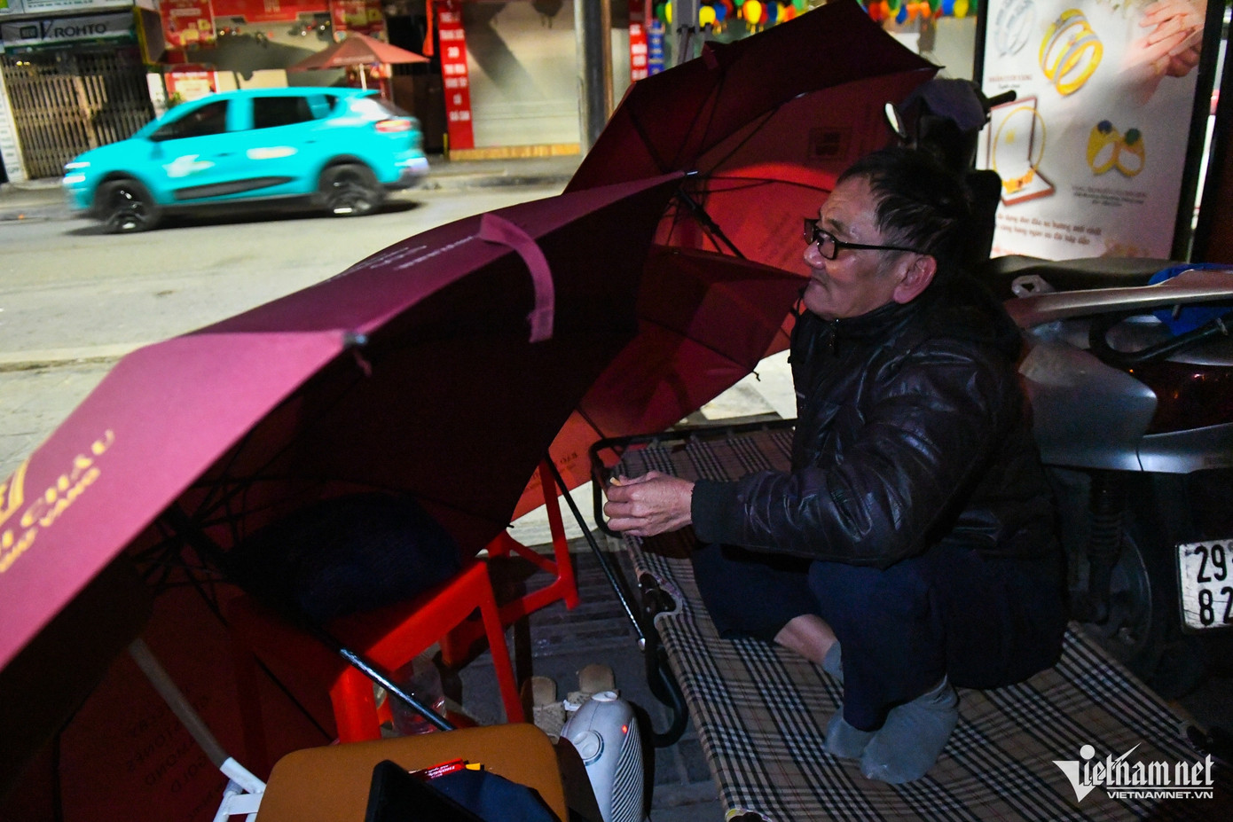 Ông Ngô Trọng Minh (bảo vệ) lúi húi dùng vài chiếc ô che chắn gió cho chiếc giường đặt trên vỉa hè phố Trần Nhân Tông. "Những ngày gần đây thường có mưa đêm, nhiệt độ hạ thấp nên rét buốt. Cứ vào mỗi ca trực đêm tôi lại che chắn như thế này để tránh gió rồi bật máy sưởi mini dưới chân để giữ ấm", ông Minh nói. Ông Ngô Trọng Minh (bảo vệ) lúi húi dùng vài chiếc ô che chắn gió cho chiếc giường đặt trên vỉa hè phố Trần Nhân Tông. "Những ngày gần đây thường có mưa đêm, nhiệt độ hạ thấp nên rét buốt. Cứ vào mỗi ca trực đêm tôi lại che chắn như thế này để tránh gió rồi bật máy sưởi mini dưới chân để giữ ấm", ông Minh nói.