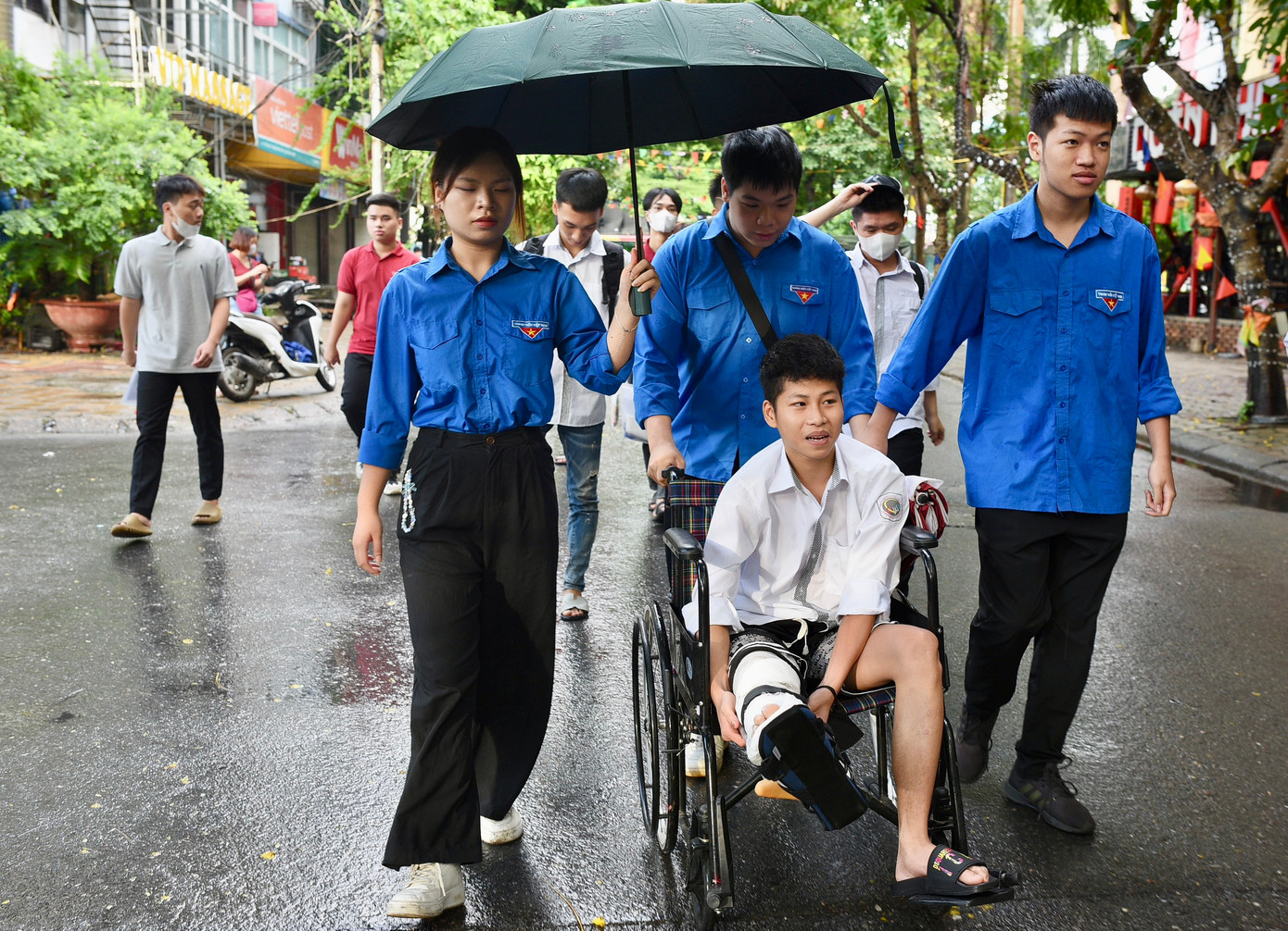 Thí sinh Nguyễn Quốc Trọng bị bó bột trước ngày thi được các tình nguyện viên hỗ trợ vào phòng thi. Ảnh: Trọng Tài