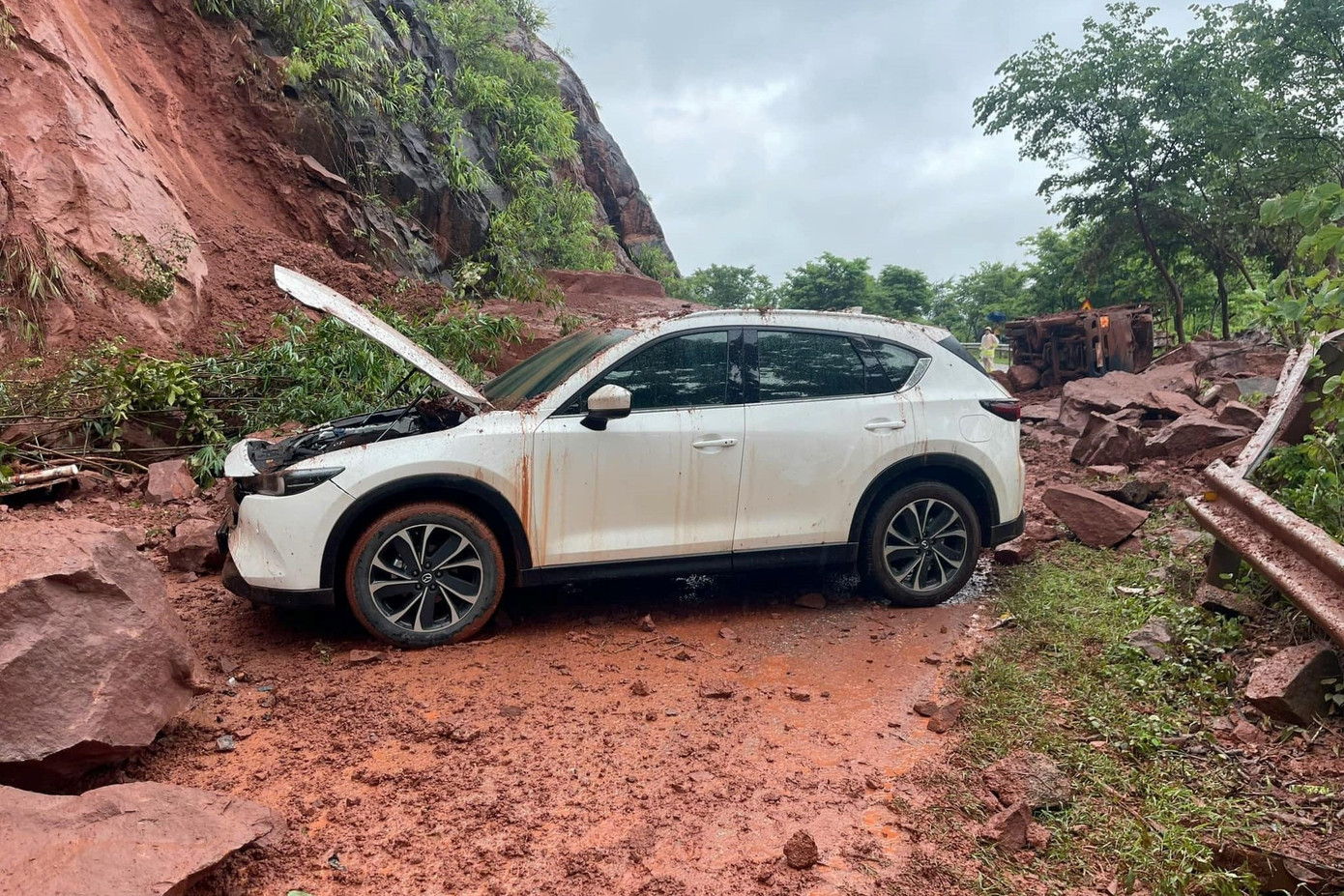 Một xe tải bị lật nghiêng trên đường, còn xe con bị đất đá va đập dẫn đến hư hỏng.