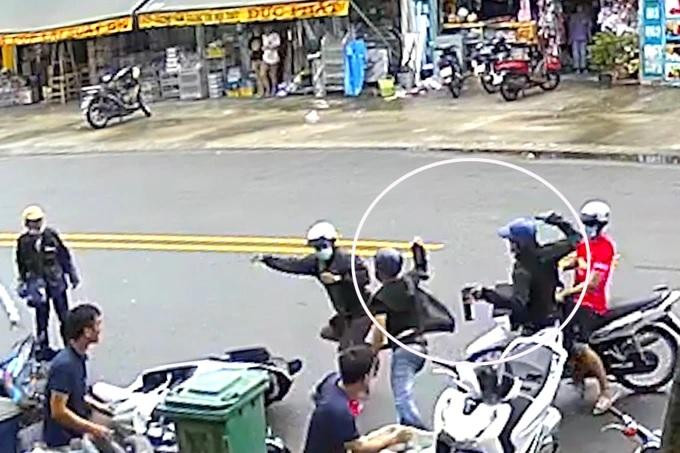 Hai kẻ trộm (vòng tròn trắng) rút dao, bình xịt hơi cay tấn công người dân (ảnh cắt từ clip).