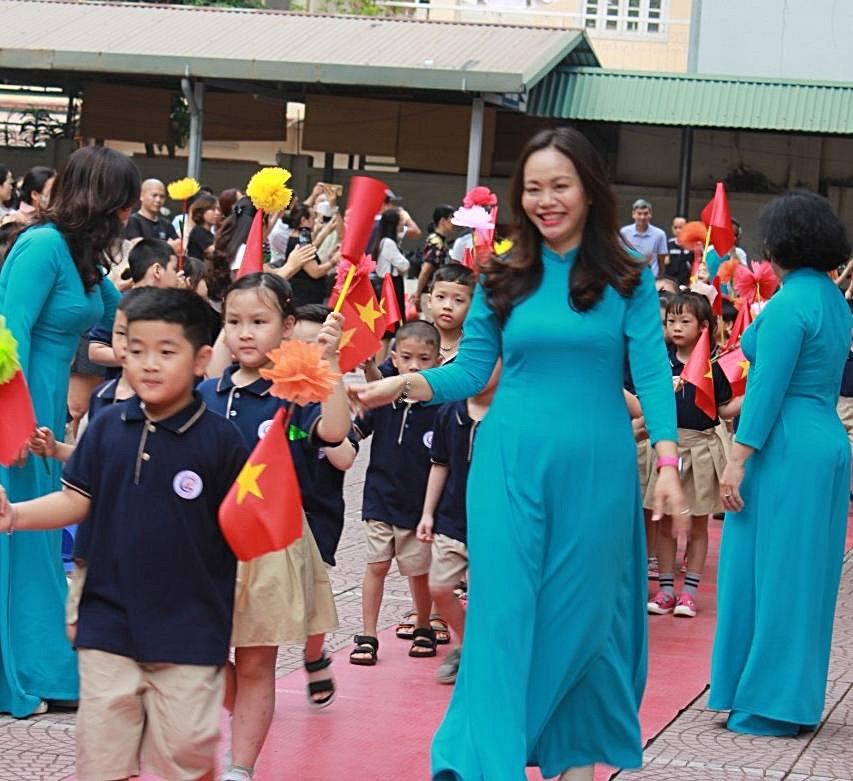 Cô Mai Tố Quyên, Hiệu trưởng nhà trường đưa học sinh lớp 1 tiến vào sân trường.