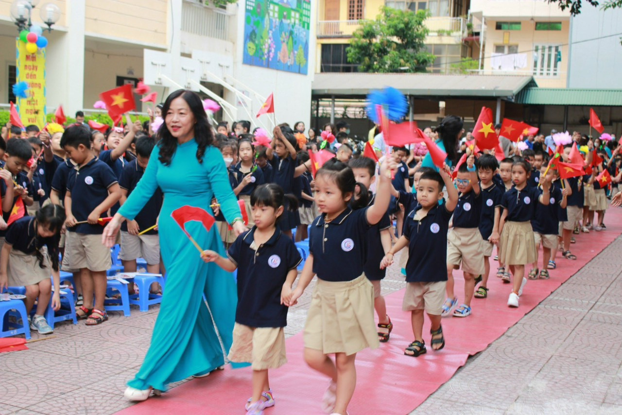 Các "tân binh" lớp 1 được cô Hiệu phó dẫn vào sân trường.