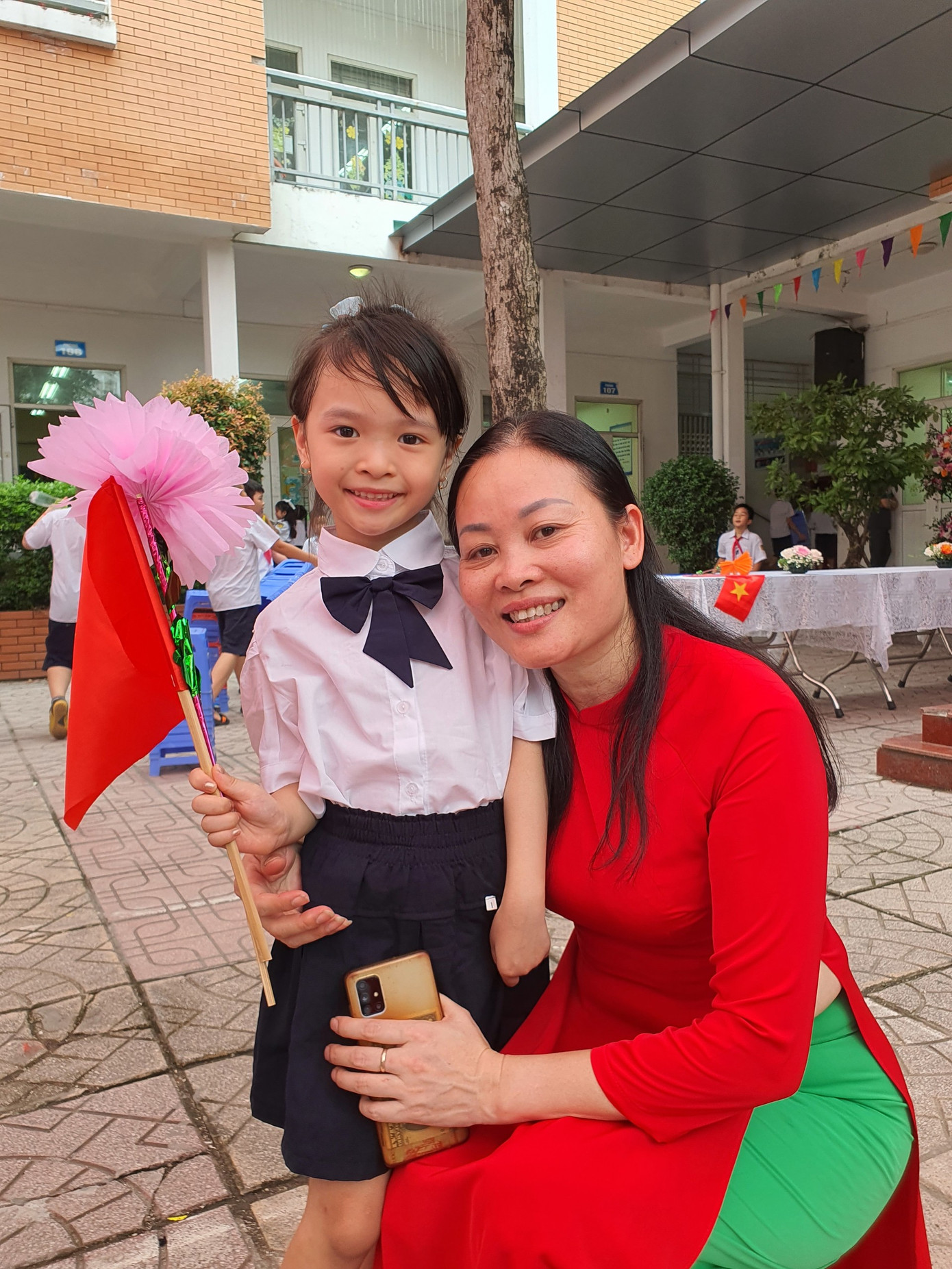 Anh Thư trong vòng tay của mẹ và cô giáo.