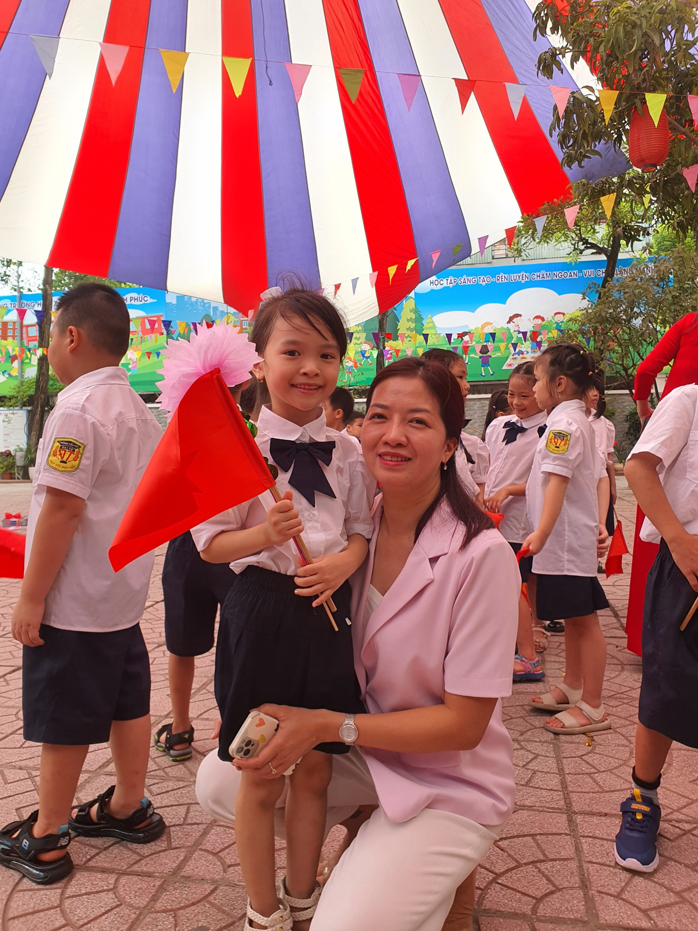 Anh Thư trong vòng tay của mẹ và cô giáo.