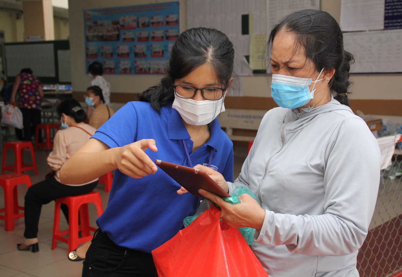 Chị Thúy hỗ trợ người dân khai báo y tế tại điểm tiêm Trường THCS Trần Quốc Toản (TP. Thủ Đức)