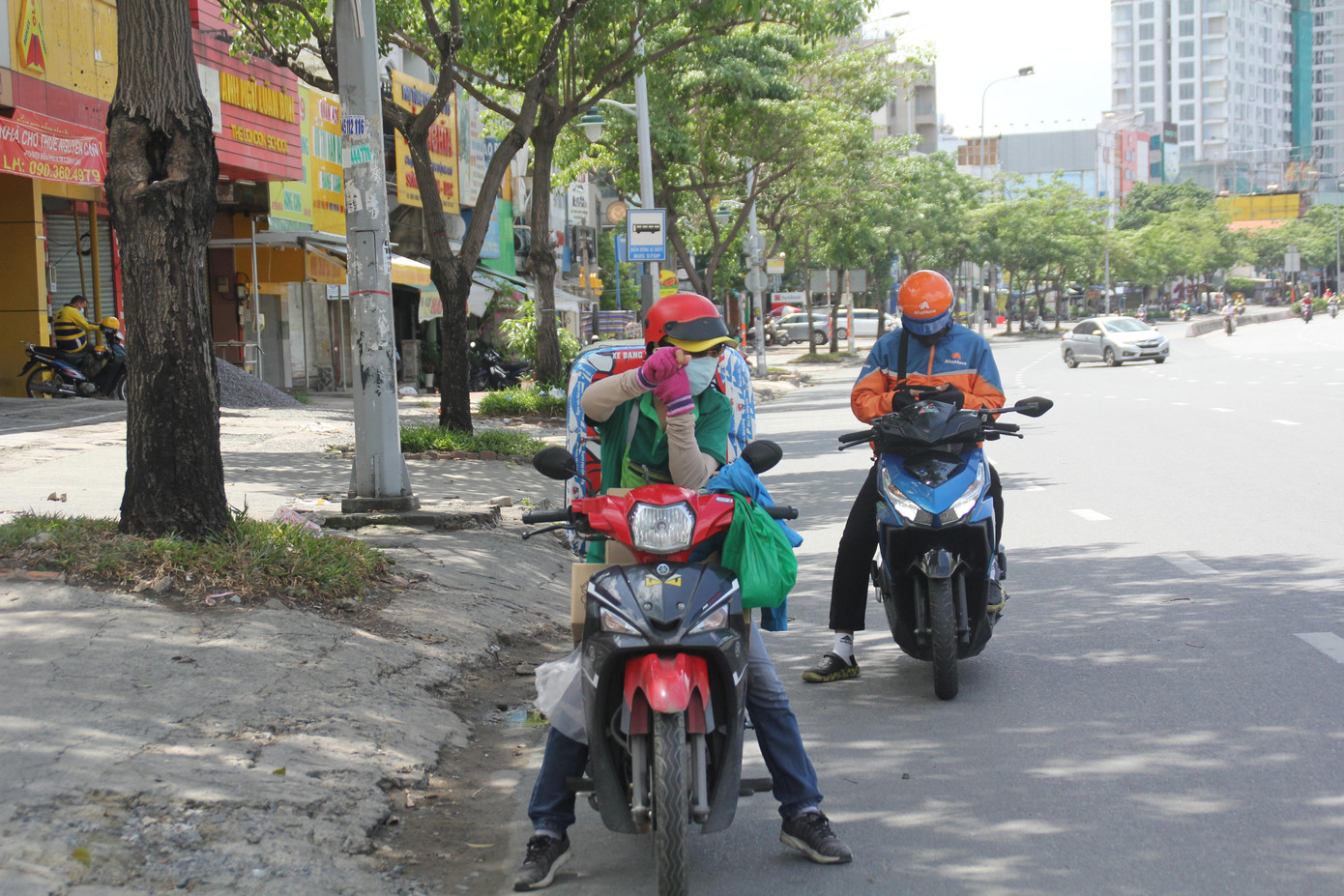 Hai shipper đang chuẩn bị giao hàng cho khách tại khu vực Hàng Xanh, quận Bình Thạnh trưa.