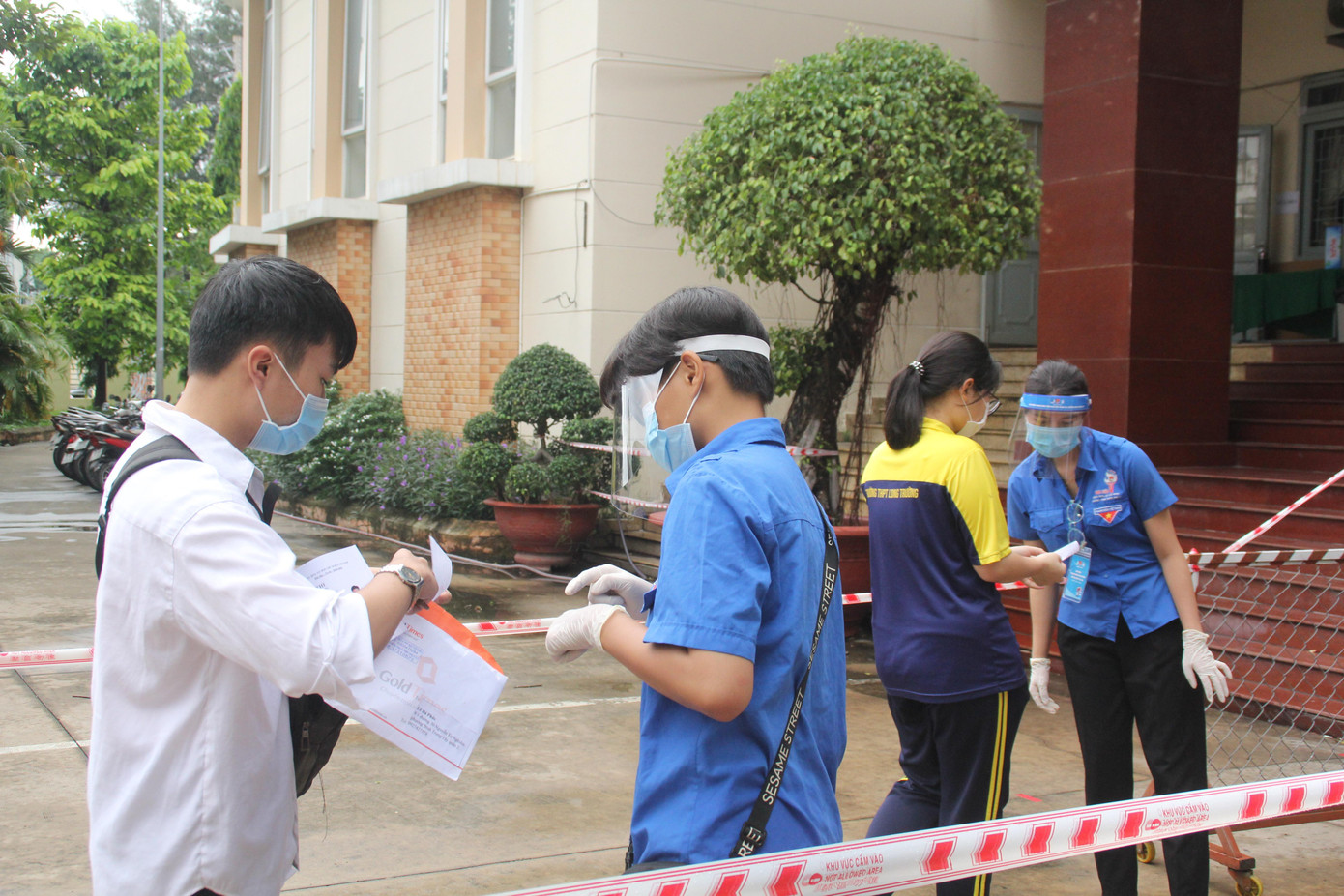 Năm nay, ngoài các vật dụng, giấy tờ cá nhân cần thiết, các thí sinh còn phải trình giấy chứng nhận xét nghiệm âm tính với virus SAR-CoV-2 thì mới được vào bên trong điểm thi. Trong ảnh: Đoàn viên thanh niên TP. Thủ Đức kiểm tra giấy chứng nhận xét nghiệm của các sĩ tử tại buổi làm thủ tục trước ngày thi.