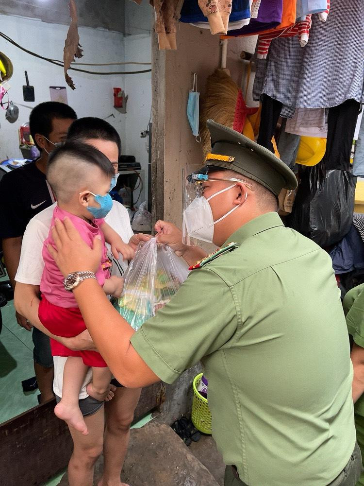 Đại úy Đặng Văn Thắng, Phó Bí thư Thường trực Đoàn Công an TPHCM gửi tặng phần quà cho một em nhỏ tại khu vực có nhiều người lao động khó khăn ở phường Tân Phong, quận 7 (Ảnh: Đoàn CATP)