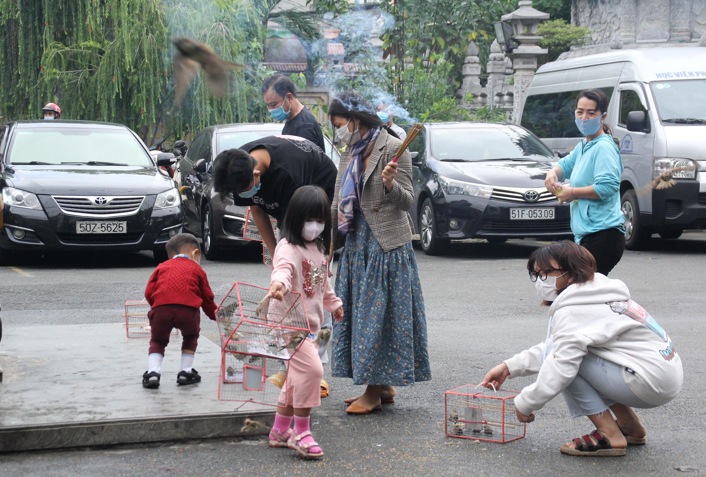 Đi chùa trong thời điểm dịch bệnh hoành hành, mọi người lớn nhỏ đều ý thức mang khẩu trang để bảo vệ sức khỏe bản thân và cộng đồng. Trong ảnh: Em nhỏ được phụ huynh hướng dẫn phóng sanh tạo phúc.