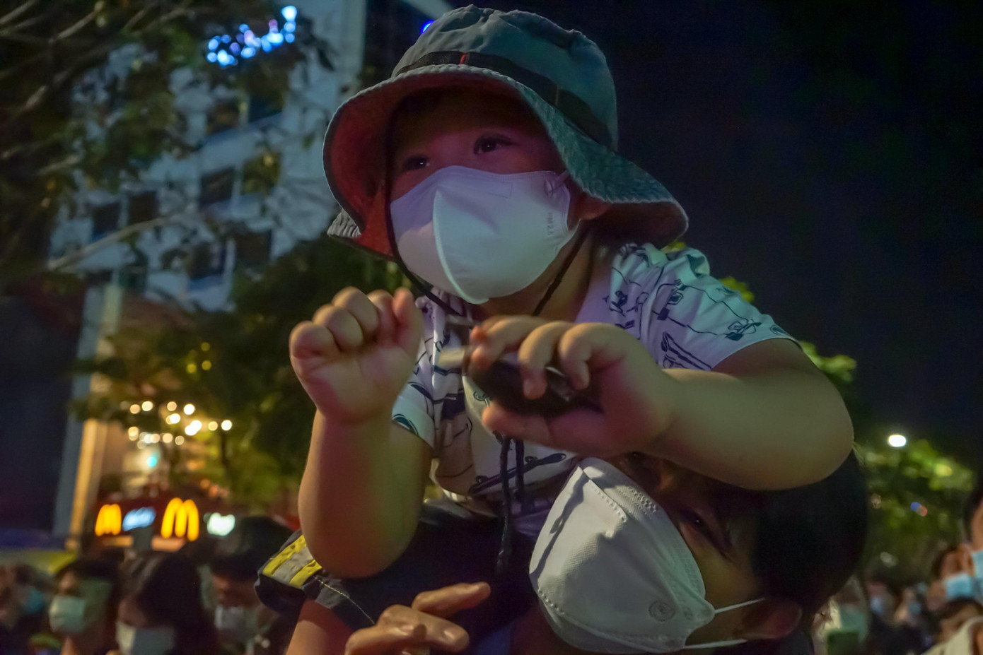 Em bé được người thân công kênh trên vai để theo dõi chương trình lễ hội diễn ra tại phố đi bộ Nguyễn Huệ.